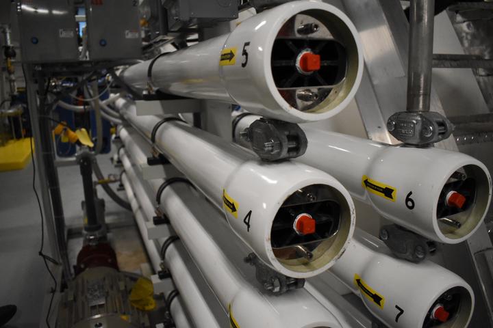 vertical rack of large white pipes with a number, yellow directional arrow, and control switches at the end of each